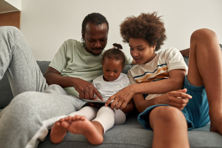 Black father point on digital tablet for childrenの写真素材