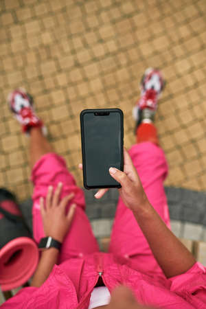 Smartphone in hand of blur disabled athletic girlの写真素材