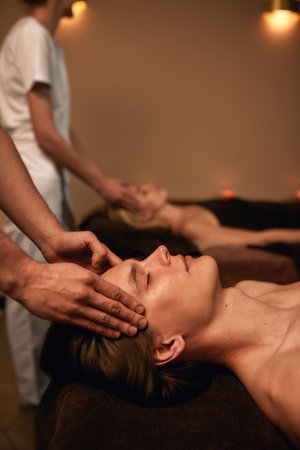 Cropped of masseurs doing head massage of coupleの写真素材
