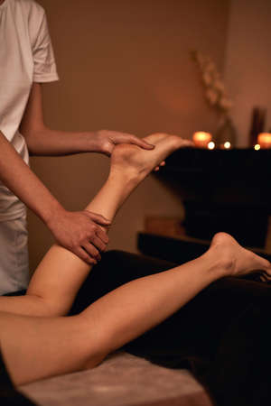 Masseur doing leg and foot massage of woman in spaの写真素材