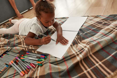 Girl drawing palm contour in notebook on floorの写真素材