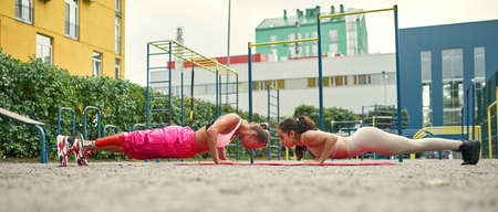 Side view of disabled girl doing plank with friend