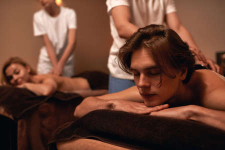 Masseurs put stones on couple back in spa salonの写真素材