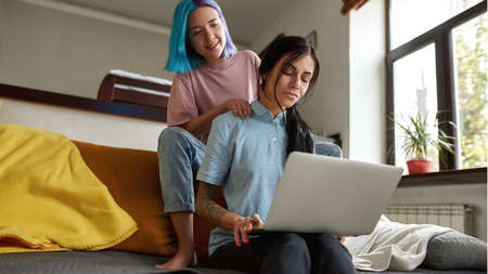 Girl do shoulder massage of girlfriend with laptopの写真素材