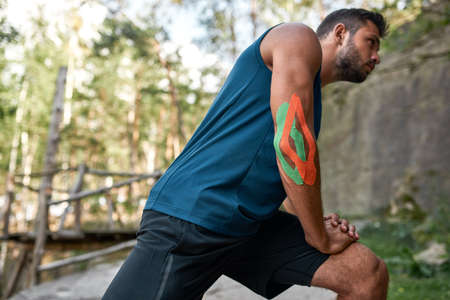 Side of young caucasian sportsman stretch outdoorsの写真素材