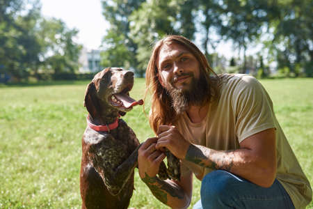 Man with Kurzhaar dog looking at camera in park