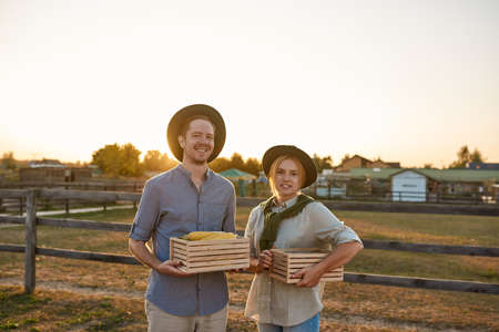 Farmer couple holding baskets with organic corn