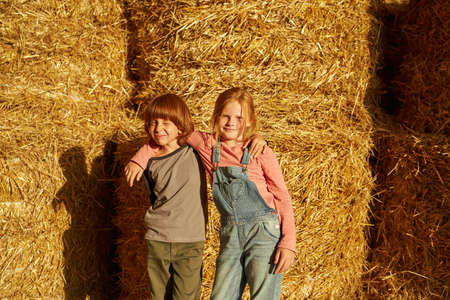 Boy and girl hugging in barn with fresh hay balesの写真素材