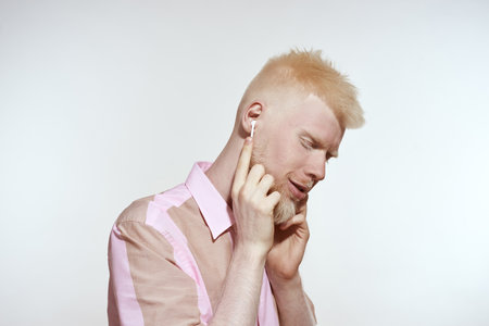 Albino guy choosing music in wireless earphonesの写真素材