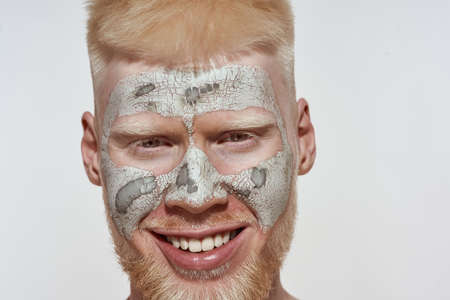 Facial close up of albino guy with dry clay maskの写真素材