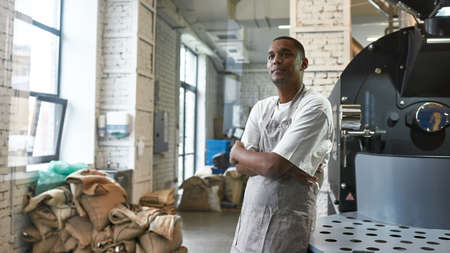 Black man near industrial coffee roasting machine