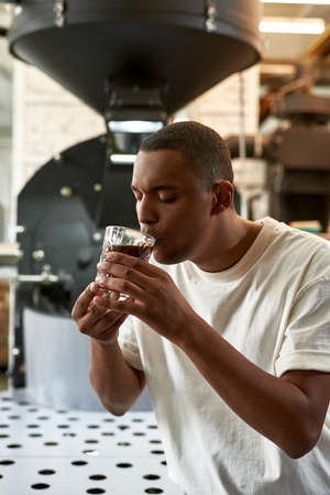 Barista drinking fresh natural coffee from glass