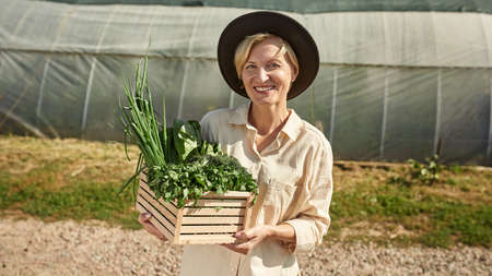 Female farmer holding basket with organic greensの写真素材