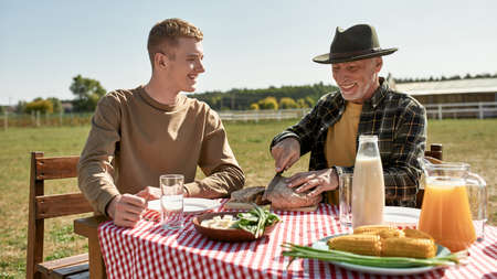 Happy farming grandfather and grandson have lunch