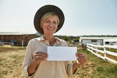 European female farmer showing empty card on farmの写真素材