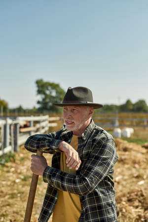 Senior male farmer with agricultural tool on farm