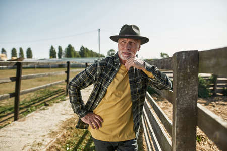 Grey hair male farmer look away at fence on ranchの写真素材