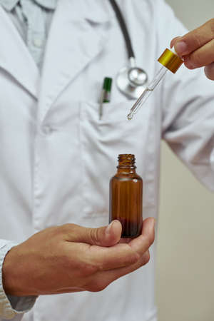 Cropped of doctor holding dropper with oil bottleの写真素材