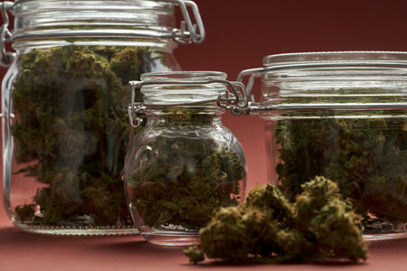 Cropped close up of glass jars with marijuana budsの写真素材