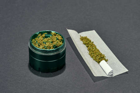Dry crushed marijuana in jar and on paper on greyの写真素材
