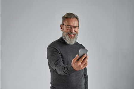Elderly smiling man have video call on smartphone