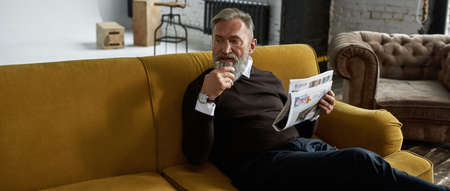 Elderly man drinking brandy and reading newspaper