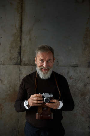 Elderly smiling caucasian man with old camera