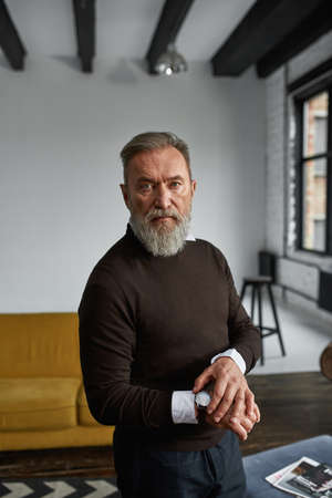 Elderly man correct wristwatch and look at cameraの写真素材