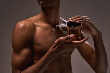 Cropped of handsome black guy hold luxury perfumeの写真素材