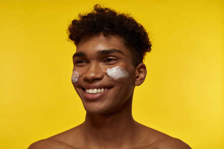 Smiling black guy with cream on his face look awayの写真素材