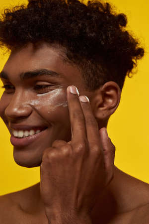 Cropped of guy smearing cosmetic cream on his face