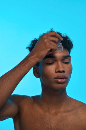 Cropped of black guy apply ice slice on his faceの写真素材