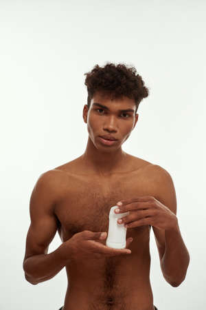 Front view of serious black guy holding deodorant