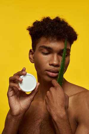 Guy hold aloe vera green leaf and cosmetic lotionの写真素材