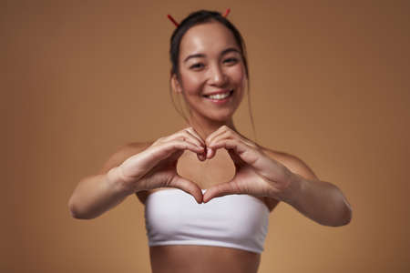 Focus of heart gesture showing blurred asian girlの写真素材