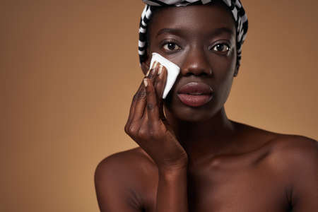 Partial of black girl wiping face with cotton swabの写真素材