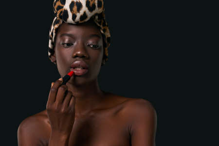 Partial of black girl painting lips with lipstick