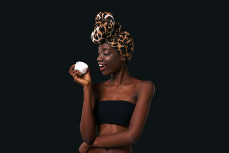 Pleased girl holding container with cosmetic cream
