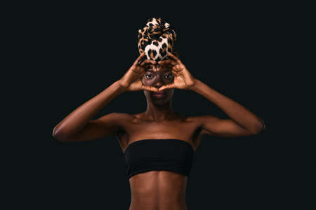 Serious black girl looking through heart gestureの写真素材