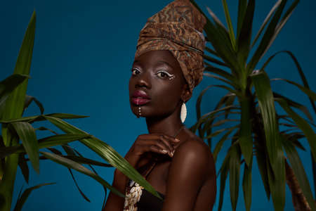 Serious elegant black girl between green palmsの写真素材