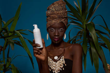 Black girl showing bottle with cream between palmsの写真素材