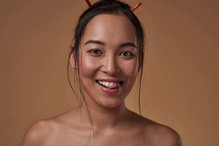 Asian girl licking oneself and looking at cameraの写真素材