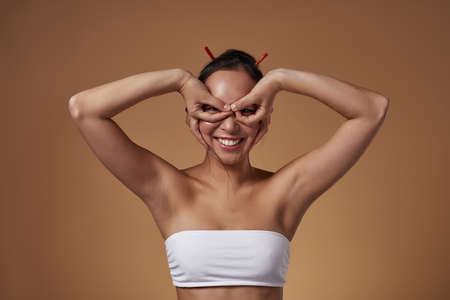 Girl show binoculars gesture and look at cameraの写真素材