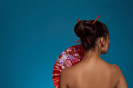 Back view of elegant asian girl with handheld fan.の写真素材