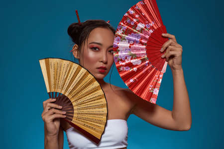 Asian girl posing with traditional handheld fansの写真素材