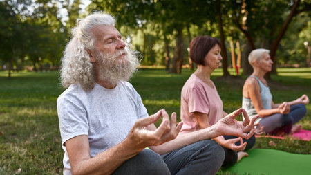 Man with blurred friends practicing yoga on lawnの写真素材