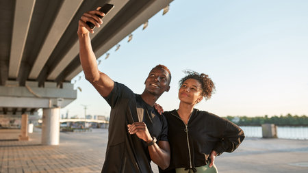 Smiling black couple taking selfie on smartphone