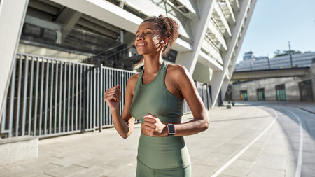 Young black sportswoman running near big stadium