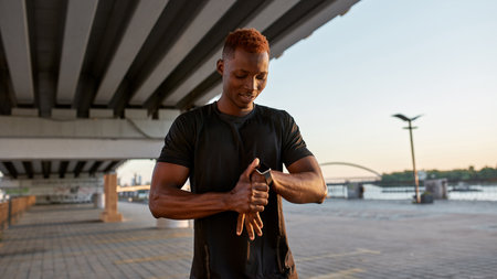 Young black sportsman browsing smartwatch on handの写真素材