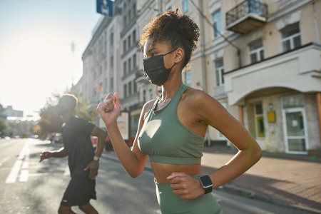 Black sports couple in medical masks run in cityの写真素材